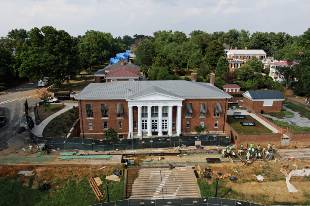 Construcción frente a un edificio universitario histórico con pilares blancos y unas escaleras.
