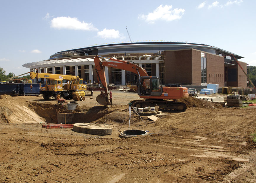 Orange excavator digging in front of basketball arena
