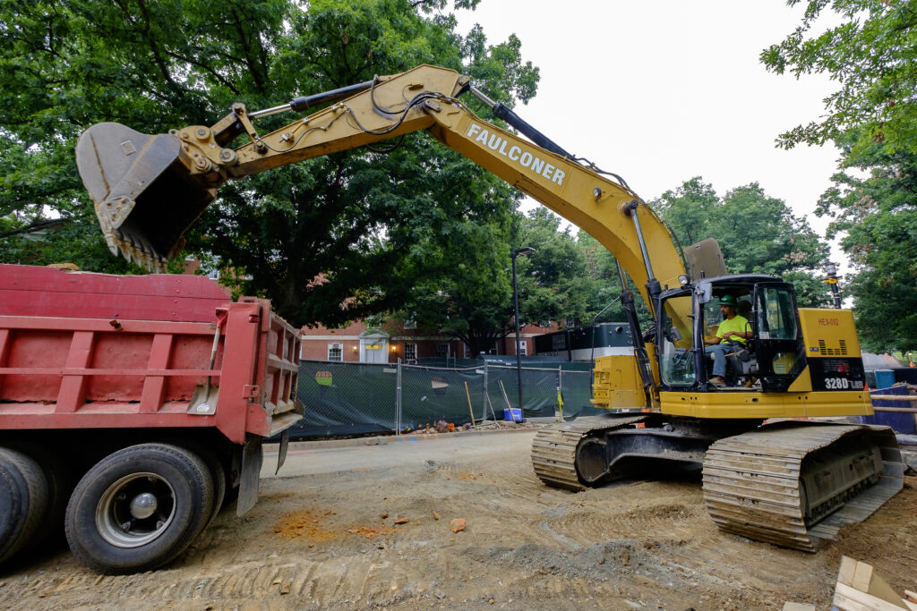 Excavator loading dirt into a red dump truck